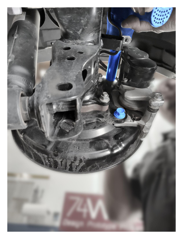 Remove rear brake caliper and set aside — do not disconnect brake lines